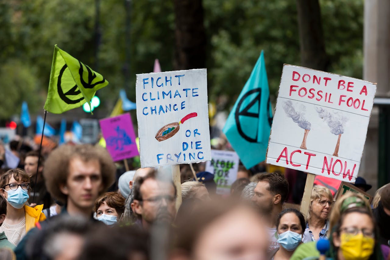 Crowd of diverse individuals at a climate change protest displaying impactful banners and flags outdoors.